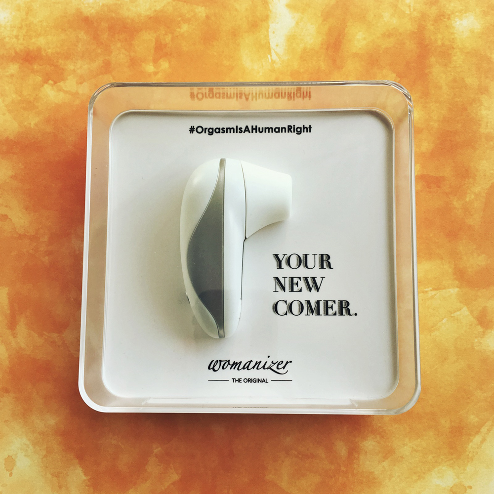 photo of white and silver womanizer starlet inside clear square box - slogan "your new comer" in black