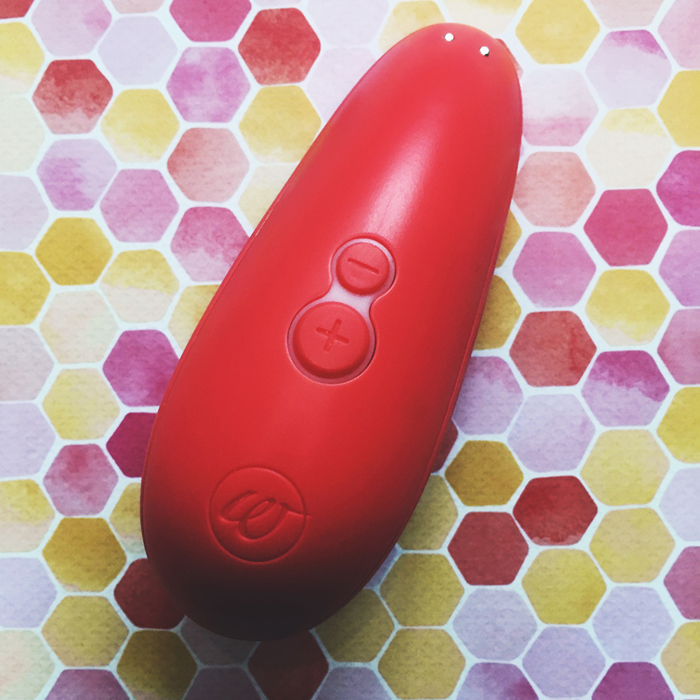 Photo of back of peach oval shaped toy showing + and - buttons and charging magnets