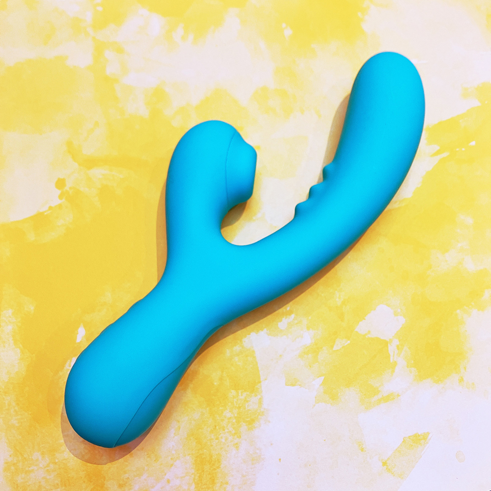 Turquoise sex toy with internal vibrator arm and external clitoral stimulator on yellow background