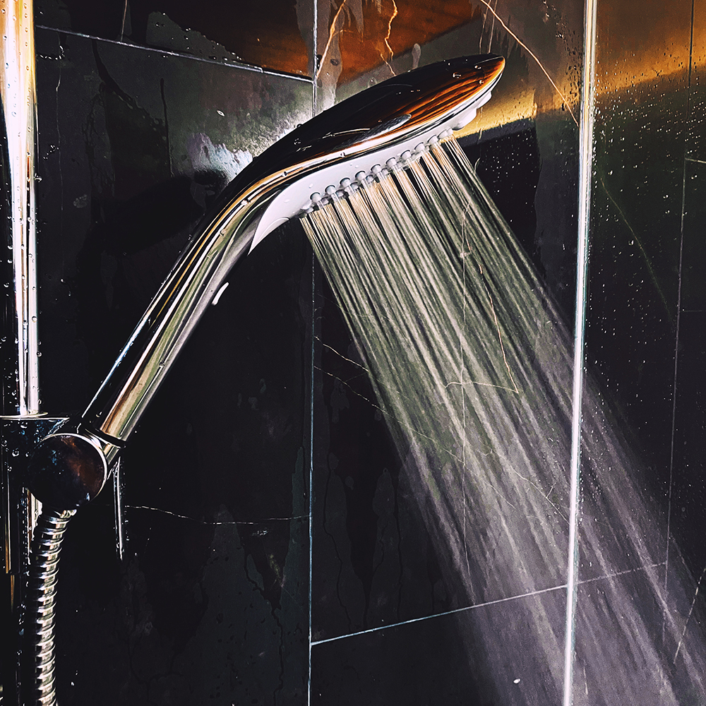 Photograph of chrome shower head running on normal "Powder Rain" setting